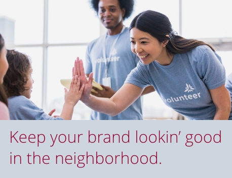 Voluteers wearing branded T-shirts high-fiving with kids. Keep your brand lookin’ good in the neighborhood.